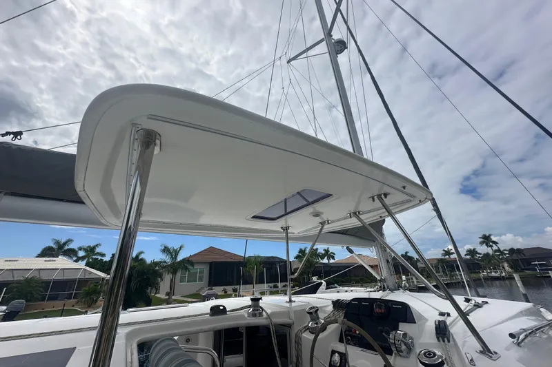 Ohana Yacht Photos Pics 2016 Leopard 44 catamaran cockpit with helm, under cloudy sky, docked near waterfront homes.