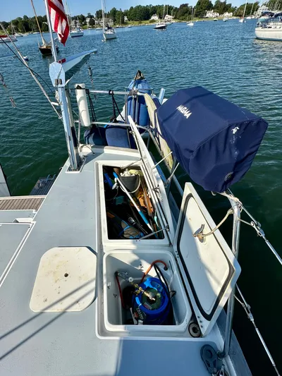 Après Yacht Photos Pics Beneteau 57 sailboat deck with open storage compartments, docked in a serene marina.