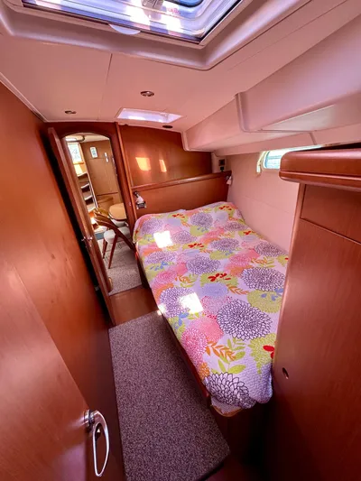 Après Yacht Photos Pics Cozy cabin interior of 2010 Beneteau 57 yacht with colorful bedding and wooden finish.