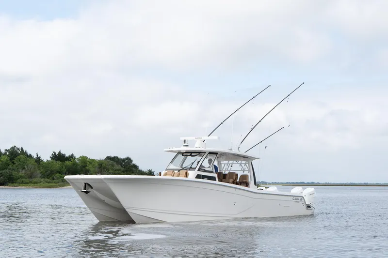  Yacht Photos Pics 2025 Caymas 44 CT boat on calm water with fishing rods, cloudy sky background.