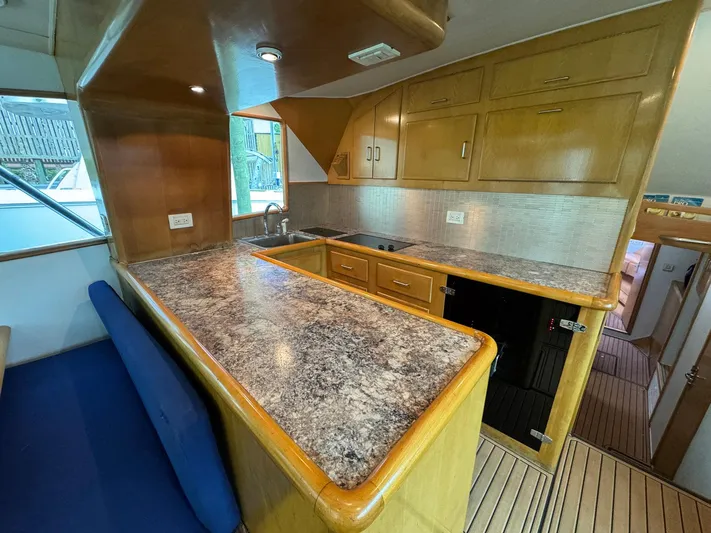 Reel Outlaw Yacht Photos Pics Luxurious 1998 Richards Yachts Custom Flybridge Sportfish kitchen with wood cabinetry and marble countertops.