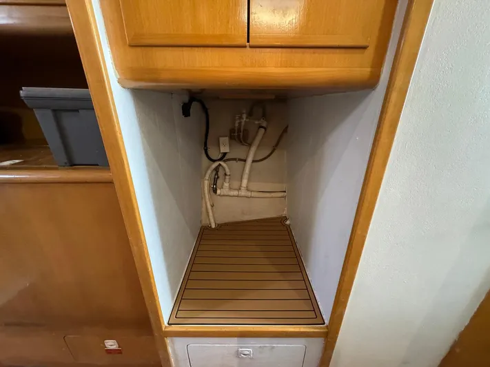 Reel Outlaw Yacht Photos Pics Empty storage compartment on 1998 Richards Yachts Custom Flybridge Sportfish, featuring wooden shelving and plumbing.