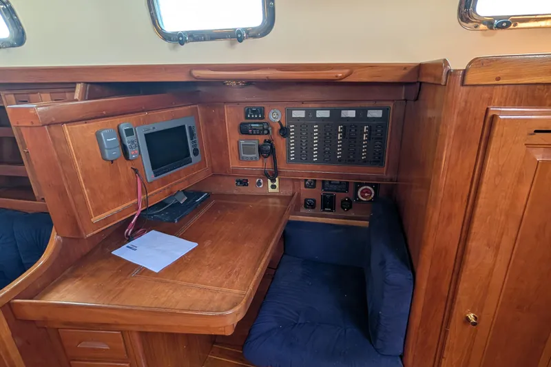 Celebration Yacht Photos Pics Navigation station in a 2001 Tartan 4100 sailboat with control panel and seating.