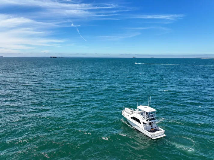 Legacy Yacht Photos Pics 2004 Cabo 40 Flybridge Convertible cruising on open ocean under clear blue sky.