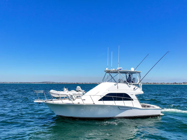 Legacy Yacht Photos Pics 2004 Cabo 40 Flybridge Convertible yacht cruising on open water under clear blue sky.