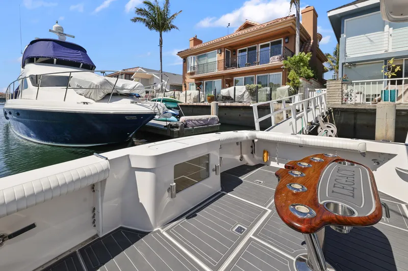 Legacy Yacht Photos Pics 2004 Cabo 40 Flybridge Convertible docked near waterfront homes, featuring spacious deck and fishing station.