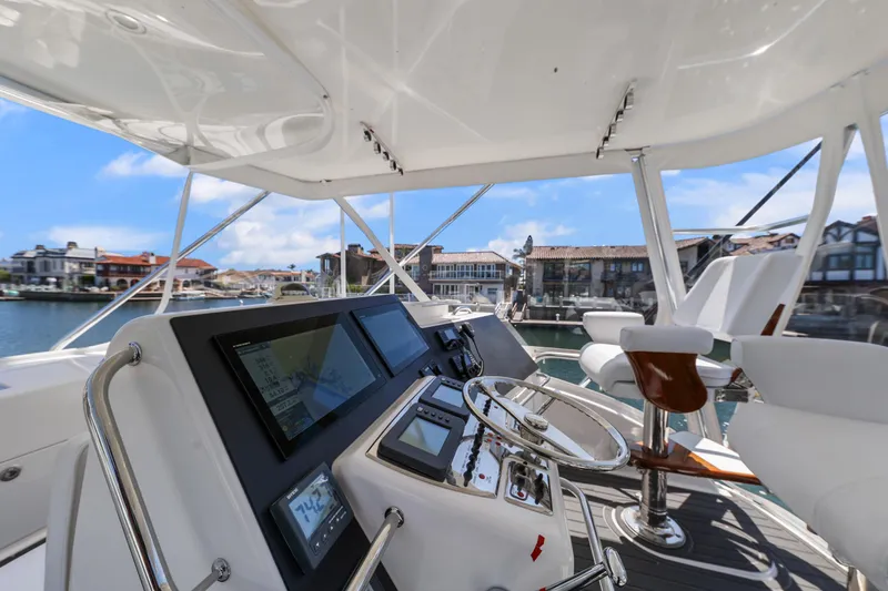 Legacy Yacht Photos Pics 2004 Cabo 40 Flybridge Convertible helm with modern controls, overlooking marina and waterfront homes.