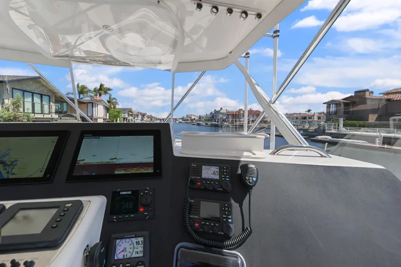 Legacy Yacht Photos Pics 2004 Cabo 40 Flybridge Convertible helm with navigation screens, overlooking waterfront homes.