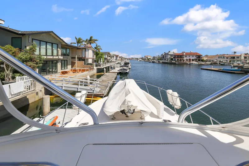 Legacy Yacht Photos Pics 2004 Cabo 40 Flybridge Convertible yacht docked in a scenic canal with waterfront homes.
