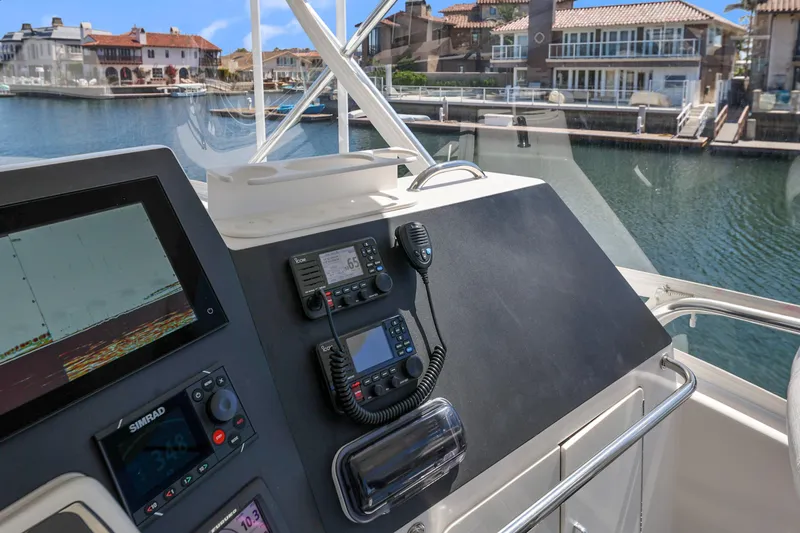 Legacy Yacht Photos Pics Cabo 40 Flybridge Convertible 2004 helm with navigation equipment, overlooking waterfront homes.