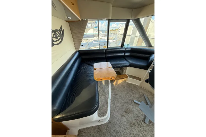 At Ease Yacht Photos Pics Interior of 1997 Bayliner 47 Motoryacht with black leather seating and wooden table.