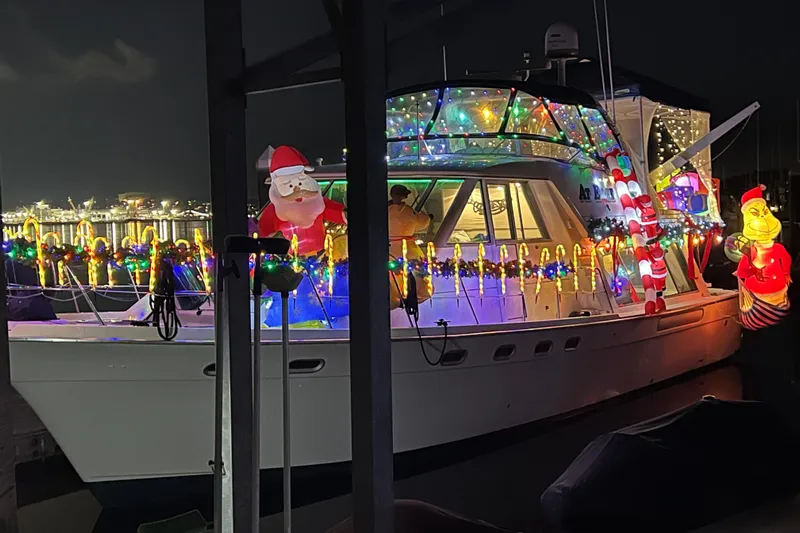 At Ease Yacht Photos Pics 1997 Bayliner 47 Motoryacht decorated with festive Christmas lights and inflatable figures at night.