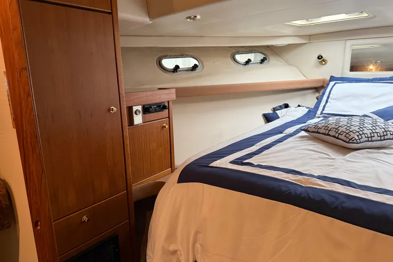 At Ease Yacht Photos Pics Interior of 1997 Bayliner 47 Motoryacht bedroom with wood cabinetry and nautical bedding.