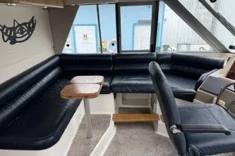 At Ease Yacht Photos Pics 1997 Bayliner 47 Motoryacht interior with black leather seating and wooden table.