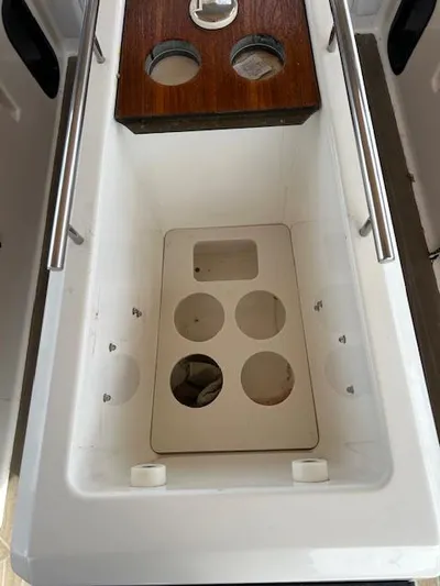 Sirene Yacht Photos Pics Storage compartment on 2019 Dufour 390 GL sailboat with circular cutouts and wooden lid.