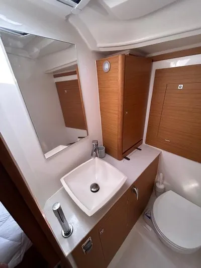 Sirene Yacht Photos Pics Modern bathroom in 2019 Dufour 390 GL yacht with sink, mirror, and wooden cabinetry.