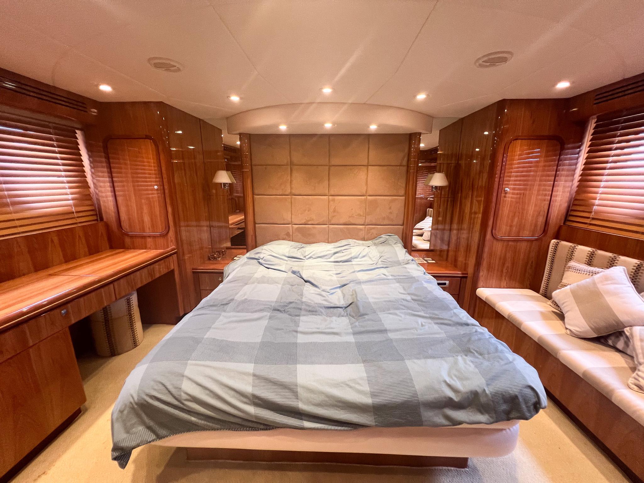 Luxurious bedroom interior of 2005 Vitech 65 yacht with wood paneling and cozy bedding.