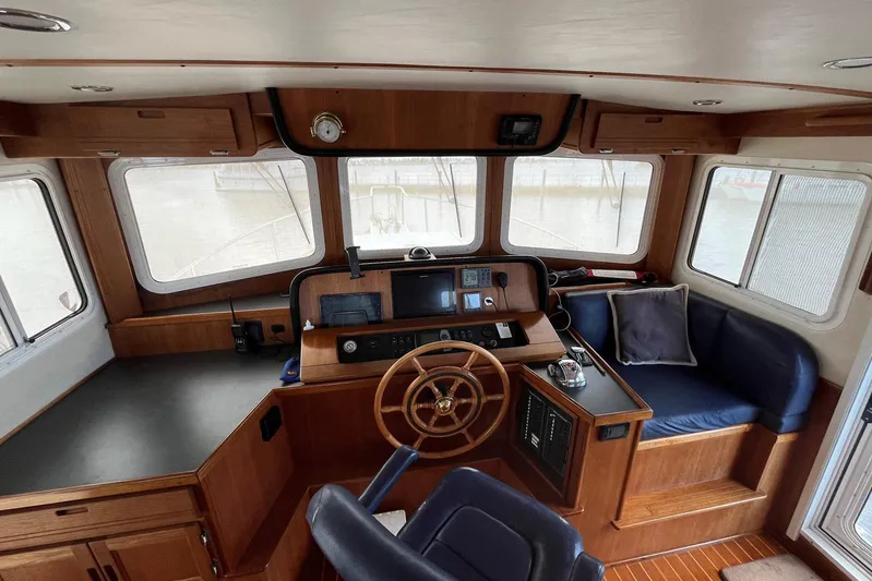 Dinky Dau Yacht Photos Pics Pilothouse of 2007 Nordic Tug 42 with wooden helm, navigation instruments, and seating area.
