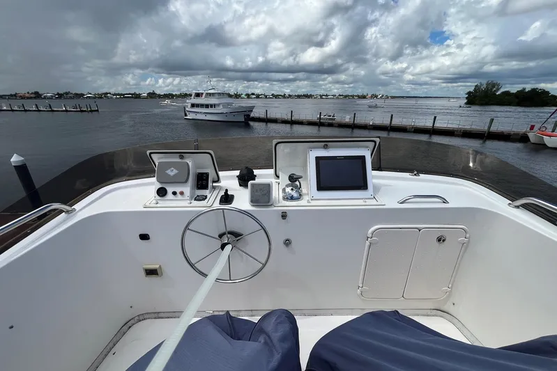 Dinky Dau Yacht Photos Pics 2007 Nordic Tug 42 helm with steering wheel and navigation equipment, docked by a scenic waterfront.