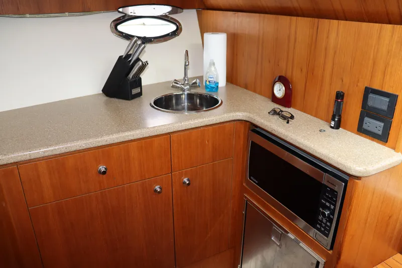 Cara Mia Yacht Photos Pics 2012 Tiara Yachts 3100 Coronet galley with sink, microwave, and wooden cabinetry.