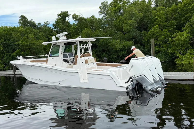 Caymas 341 Center Console Yacht Photos Pics 2020 Caymas 341 CC boat docked with triple Mercury engines, surrounded by lush greenery.