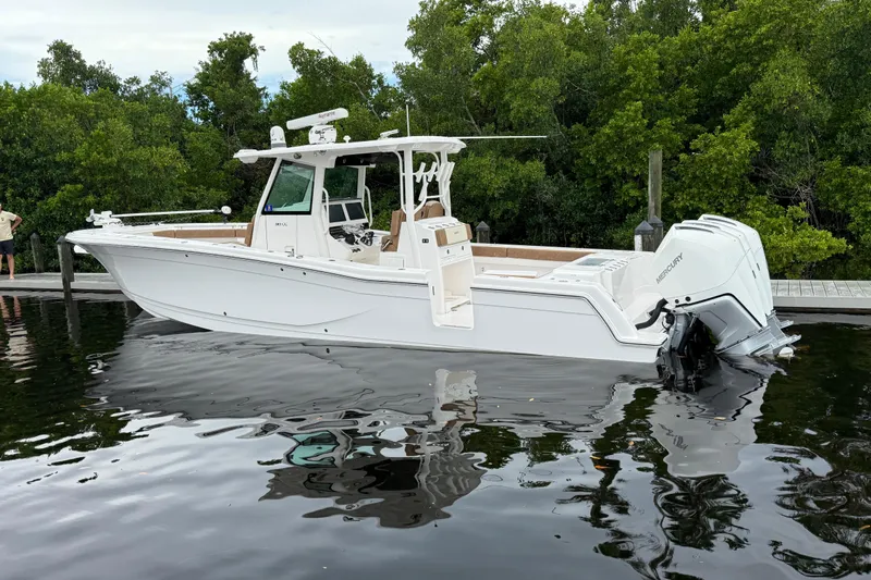 Caymas 341 Center Console Yacht Photos Pics 2020 Caymas 341 CC boat docked on calm water with lush greenery background.