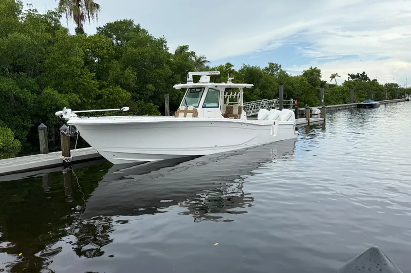 Caymas 341 Center Console Yacht Photos Pics 2020 Caymas 341 CC boat docked on calm water, surrounded by lush greenery.