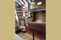 Interior of a 1935 Matthiesen & Paulsen Sloop, featuring wooden cabinetry and portholes.