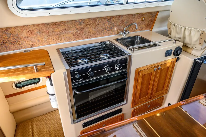  Yacht Photos Pics Compact kitchen in 2012 Aspen C90 boat with stove, sink, and wooden cabinets.