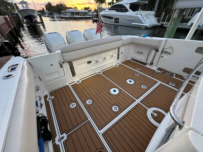  Yacht Photos Pics 2017 Boston Whaler 370 Outrage boat deck with wooden flooring, docked at sunset.