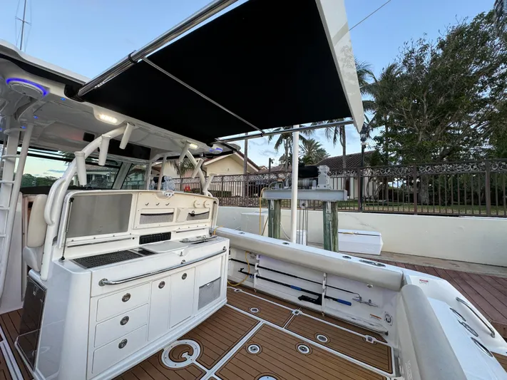  Yacht Photos Pics 2017 Boston Whaler 370 Outrage boat with outdoor kitchen and canopy, docked near a house.