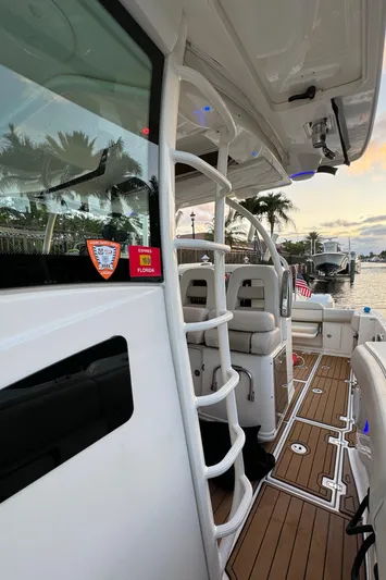  Yacht Photos Pics 2017 Boston Whaler 370 Outrage boat interior with seating and ladder, docked by palm trees.