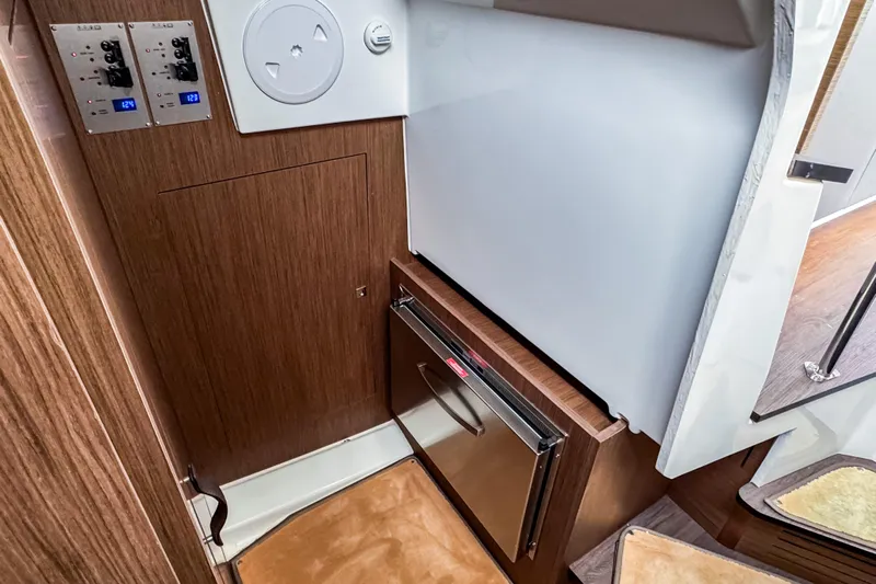  Yacht Photos Pics Interior of 2022 Beneteau Antares 11 Fly, featuring wood paneling and compact fridge.