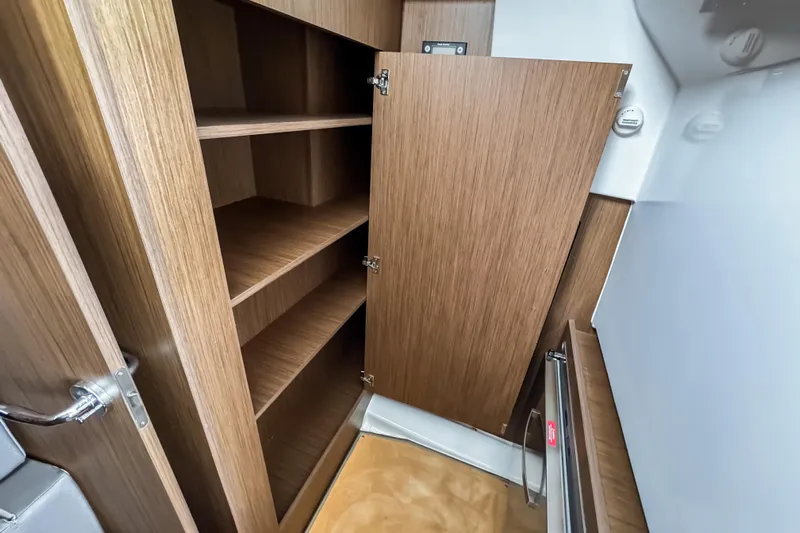  Yacht Photos Pics Interior storage cabinet on 2022 Beneteau Antares 11 Fly boat, featuring wooden shelves.
