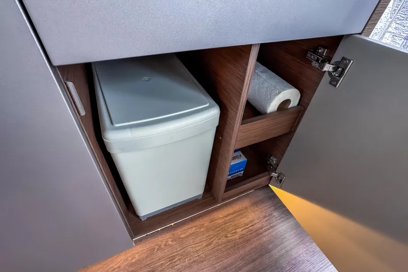  Yacht Photos Pics Cabinet storage in 2022 Beneteau Antares 11 Fly, featuring trash bin and paper towel.