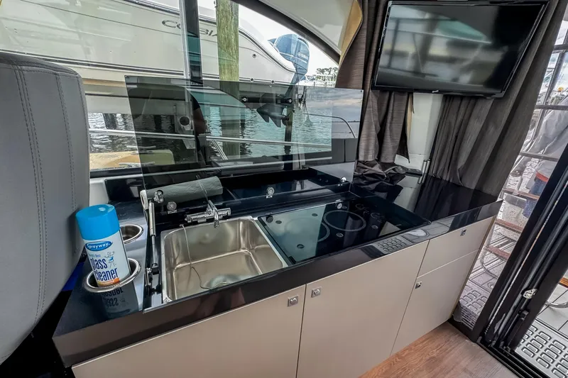  Yacht Photos Pics Interior of 2022 Beneteau Antares 11 Fly with kitchenette and TV, docked by water.