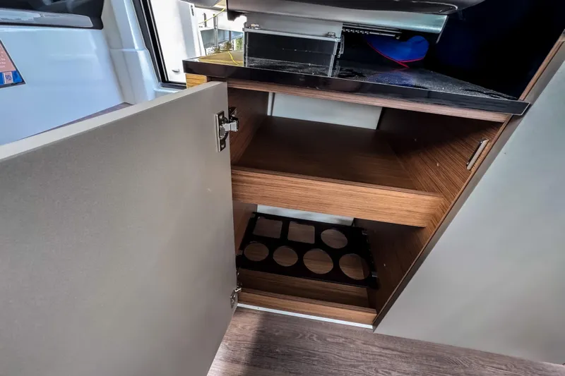  Yacht Photos Pics Open cabinet in 2022 Beneteau Antares 11 Fly, showcasing wooden shelves and storage space.