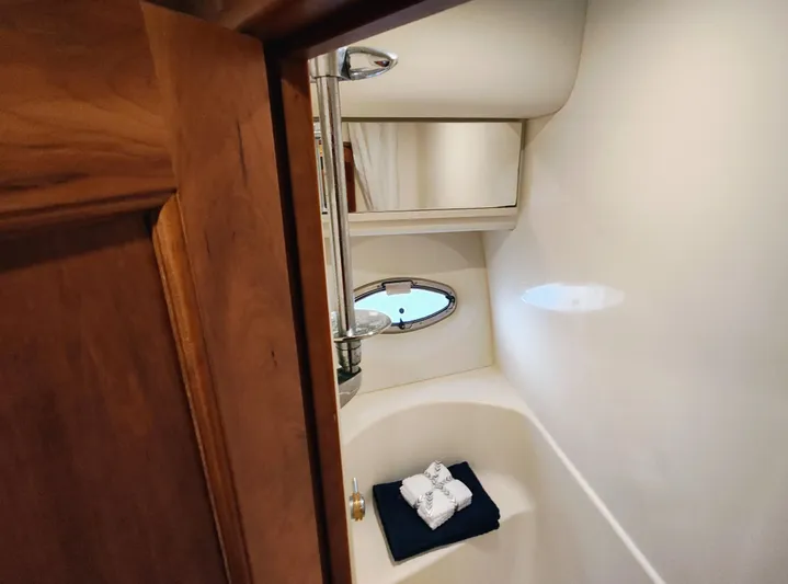 Diversion III Yacht Photos Pics Luxurious bathroom interior of 2002 Silverton 43 Motor Yacht with wooden door and porthole window.