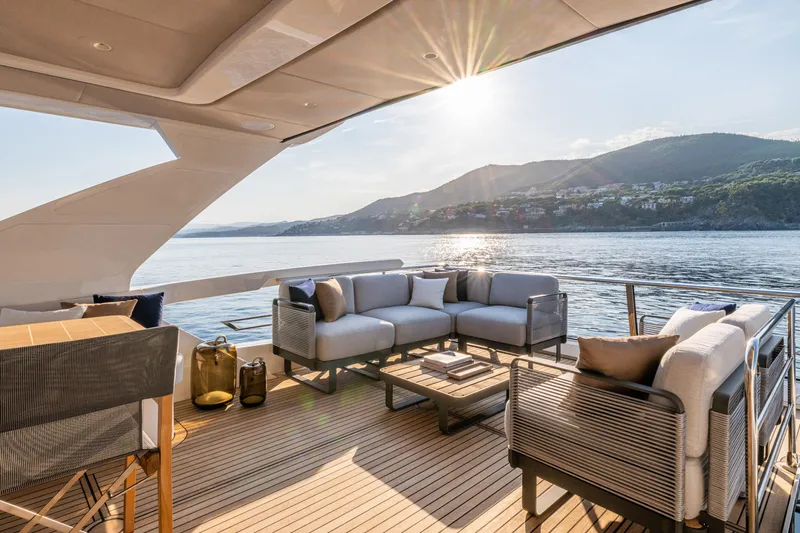  Yacht Photos Pics Luxurious 2026 Absolute Navetta 62 yacht deck with elegant seating, ocean view, and sunset backdrop.