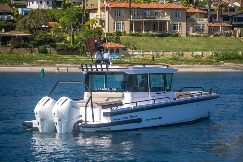  Yacht Photos Pics 2022 Axopar 28 Cabin boat cruising near a scenic coastal mansion.