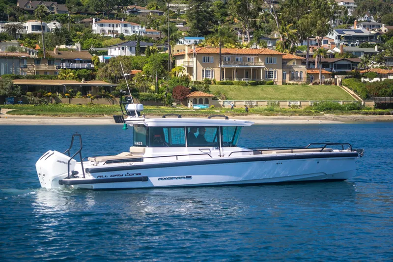  Yacht Photos Pics 2022 Axopar 28 Cabin boat cruising near scenic coastal homes.