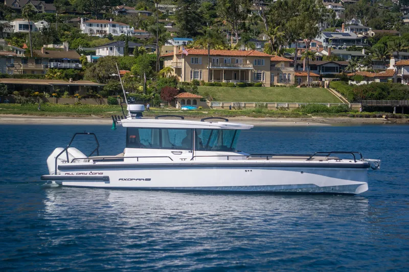  Yacht Photos Pics 2022 Axopar 28 Cabin boat cruising near scenic waterfront homes.