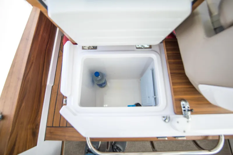  Yacht Photos Pics 2022 Axopar 28 Cabin cooler with a water bottle inside, featuring wooden accents.