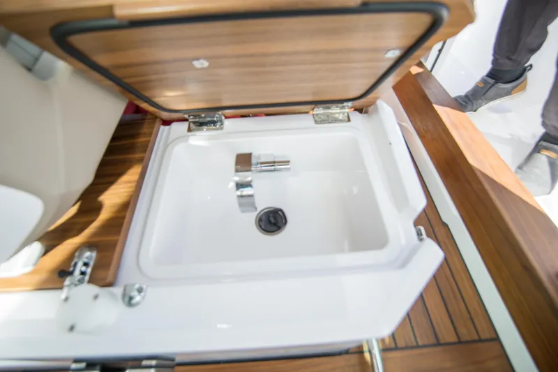  Yacht Photos Pics 2022 Axopar 28 Cabin sink with wooden cover and modern faucet.