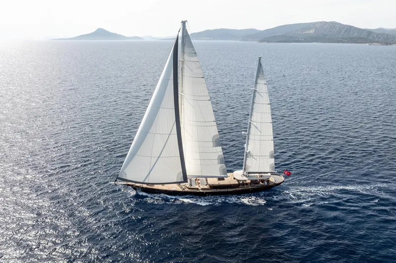 Sallyna Yacht Photos Pics 2023 Su Marine sailing yacht gliding on open sea with distant mountains.