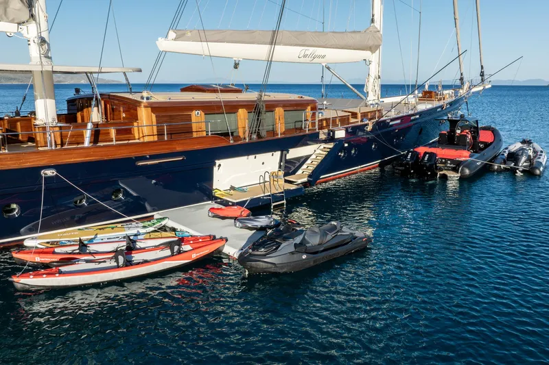 Sallyna Yacht Photos Pics Luxurious 2023 Su Marine sailing yacht with watercraft and kayaks docked in serene blue waters.