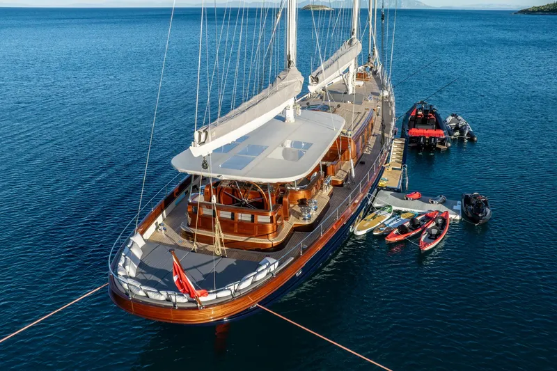 Sallyna Yacht Photos Pics Luxurious 2023 Su Marine sailing yacht with paddleboards and boats on calm blue water.