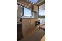 Interior of 2024 Nimbus 365 Coupe boat with modern wood cabinetry and scenic window view.