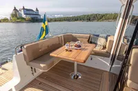 2024 Nimbus 365 Coupe deck with table, Swedish flag, and scenic lake view.