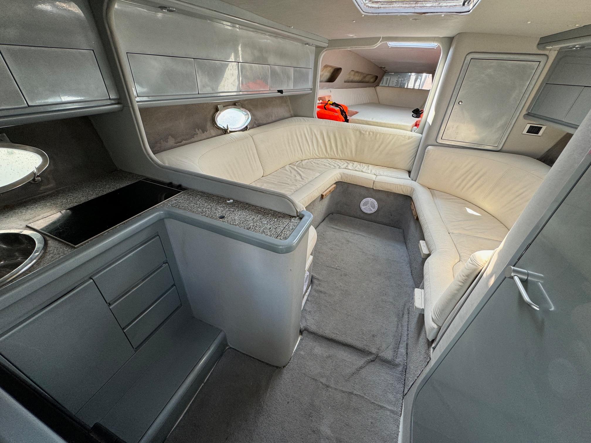 Interior of a 1997 Performance 1107 boat with modern seating and compact kitchen area.
